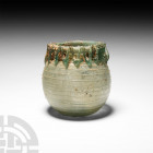 Roman Green Glass Vessel with Trail. 3rd-4th century A.D. A blue-green glass jar with bulbous body, rolled rim, applied zigzag trail at the neck with ...