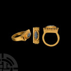Late Roman Architectural Gold Ring with Gemstone. 4th-6th century A.D. A gold ring with rectangular-section hoop, rectangular bezel with openwork side...