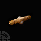 Double Phallic Bead Pendant. 1st millennium B.C. A carved agate tubular bead with each terminal formed as a stylised phallus, a single pair of testicl...