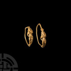 Hellenistic Gold Eros Earring. 2nd-1st century B.C. A gold earring with a wire hoop with applied figure of Eros standing nude with hands on his hips, ...