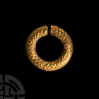 Achaemenid Gold Hair Ring. c.5th century B.C. A hollow-formed penannular hair ornament with repoussé lattice to the hoop, one end pierced to accept a ...