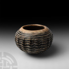 Marvered Glass Vessel. c.13th century A.D. A glass vessel composed of a rounded body with medial ribs and rounded base, manganese body marvered and tr...