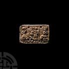 Sumerian Faience Plaque. 3rd millennium B.C. A composition rectangular plaque bearing figural scene composed of two figures beside a table, a seated f...