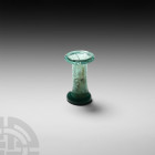 Roman Green Glass Cotton Reel Unguentarium. 2nd-4th century A.D. A green glass perfume bottle or unguentarium of cotton-reel form. 11.6 grams, 41 mm (...