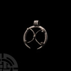 Roman Silver Lunar Pendant. 1st-3rd century A.D. A silver lunular pendant composed of a round-section crescentic body bearing openwork silver wire X-m...