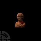 Western Asiatic Baltic Amber Bust Pendant. 9th-12th century A.D. A pendant carved in amber depicting a female bust modelled in the round with high-rel...