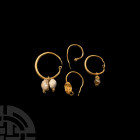Roman Gold Earring Collection. 1st-3rd century A.D. A mixed group of four gold hoop earrings comprising one with a facetted stud terminal; one with a ...
