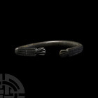Roman Bracelet with Decorated Terminals. 1st-3rd century A.D. A bronze penannular bracelet with lozenges and hatched panels to the outer face. 19.9 gr...