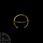 Romano-British Torc-Shaped Brooch. 1st century B.C.-1st century A.D. A torc-shaped brooch with a slender round-section body and globular terminals wit...