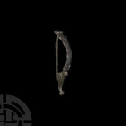 Large Roman Aucissa Bow Brooch with Wolf's Face. 1st-2nd century A.D. A large bronze Aucissa variant type bow brooch with annulet decoration to the he...