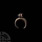 Roman Silver Lunar Pendant. 1st-3rd century A.D. A silver lunular pendant composed of a tapering keeled body and ribbed suspension loop. 1.78 grams, 1...