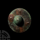 Luristan Shield Boss. 9th-6th century B.C. A bronze discoid shield boss with raised and domed centre, repoussè border with later added eagles; central...