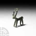 Luristan Stag Figurine. 13th-6th century B.C. A bronze figure modelled as a stylised standing stag with bars between the feet, notches to the tall ant...