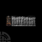 Mesopotamian Cylinder Seal with Standing Figures. 3rd-2nd millennium B.C. A small jasper cylinder seal drilled for suspension, bearing an incuse stand...