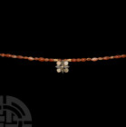 Elamite Silver Flower Pendant Necklace. 1st millennium B.C. A restrung necklace of fusiform and oval carnelian beads with centrepiece a silver cloison...