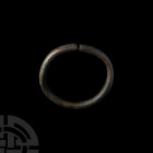 Decorated Arm Ring. 1st millennium B.C. A substantial heavy bronze penannular arm ring composed of a round-section hoop with waisted arms, the exterio...