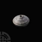 Persian Spindle Whorl. Iron Age II, 11th-6th century B.C. A conical grey limestone spindle whorl with a flat base and circumferential groove to the up...