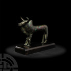 Bronze Bull Statuette. 1st millennium B.C. A bronze figure of a standing zebu bull with head raised, crescent horns above raised lozenge eyes, incised...