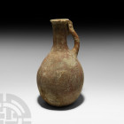 Luristan Wine Jug with Animal Handle. 13th-7th century B.C. A terracotta jug with globular body, cylindrical neck and everted rim, strap handle with t...