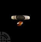 Banded Agate Bead Group. 1st millennium B.C. and later. A pair of banded agate beads comprising: one oval bead and one fusiform bead; each drilled lon...