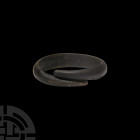 Bronze Age Decorated Bracelet. 2nd millennium B.C. A coiled bracelet with D-section body and tapering terminals, the outer face engraved with diagonal...