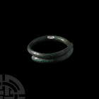 British Bronze Age Decorated Bracelet. c.600 B.C. A bracelet composed of a carinated body with overlapping arms, the exterior decorated with linear mo...