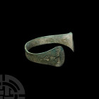 Viking Age Stamp-Decorated Bracelet. 9th-11th century A.D. A penannular bronze bracelet composed of a flat-section body and expanding terminals, stamp...