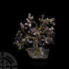 Amethyst Crystal Gem Tree. A gemstone tree consisting of a brass trunk and branches tipped with polished amethysts, mounted on a section of amethyst g...