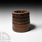 Tribal Spice Mortar with Iron Rim. 19th century A.D. A wooden spice mortar composed of a barrel-shaped body with slight taper, iron band to the rim, f...