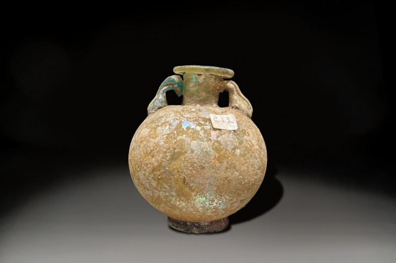 LARGE GLASS GLOBULAR BOTTLE WITH TWIN HANDLES AND BASE, ROMAN PERIOD 200 - 400 A...