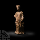 Greek Terracotta Standing Figure 5th-3rd century B.C. A terracotta standing female figure dressed in a floor-length himation, hair drawn back and arra...