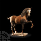 Chinese Tang Prancing Horse Tang Dynasty, 618-907 A.D. A ceramic horse modelled prancing, with naturalistic anatomical detailing, flowing mane, dresse...