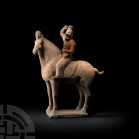Chinese Tang Horse and Rider Figure Tang Dynasty, 618-907 A.D. A ceramic horse standing on a tapering rectangular base, mounted by a rider in a dynami...