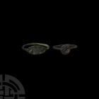 Greek Ring Group 5th-3rd century B.C. A group of two bronze finger rings with slender hoops, one with an elliptical bezel bearing a kneeling figure wi...