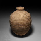 Roman Ribbed Amphora 1st-2nd century A.D. or later. A squat ceramic jar with tapering body and broad shoulder with horizontal ribbing, short neck with...