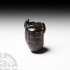 Roman Rod-Formed Glass Vessel Circa 4th century A.D. A small, rod-formed black glass jar with globular body and two handles, decorated with indented v...