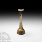 Roman Glass Candlestick Unguentarium 1st-3rd century A.D. A clear glass candlestick unguentarium composed of a domed lower body, tall cylindrical neck...