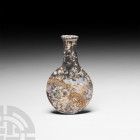 Roman Glass Flask 2nd-4th century A.D. A glass bottle of flask form; iridescent surfaces. 7.2 grams, 66 mm (2 5/8 in.). Ex Dr D.G. Surrey, deceased. [...