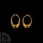 Western Asiatic Gold Earring Pair 1st millennium B.C. A matching pair of gold earrings, each composed of a flat-section, crescentic body with coiled w...