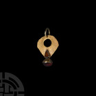 Gold and Gemstone Pendant Early 1st millennium A.D. A bifacial pendant comprising an openwork sheet-gold body, both faces with a raised triangular cel...