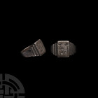 Western Asiatic Silver Ring with Desert Scene 20th century A.D. A silver finger ring with stepped shoulders, rectangular bezel with incuse scene of a ...