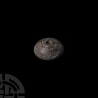 Western Asiatic Dark Grey Stone Spindle Whorl Late 1st millennium B.C. A dark grey stone spindle whorl of domed form, circle engraved around the centr...