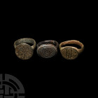 Medieval Ring Group 12th-15th century A.D. A group of three bronze finger rings bearing various designs on the bezels: crosses embellished with hatchi...