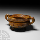 Medieval Glazed Tripod Vessel 15th-16th century A.D. A glazed ceramic tripod vessel with carinated body and everted rim, integral handles, stub legs w...