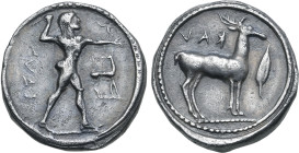Bruttium, Kaulonia AR Stater. Circa 475-425 BC. Nude Apollo walking to right, holding laurel branch in upright right hand, small daimon running to lef...