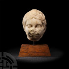 Roman Marble Head of Cupid
2nd-3rd century A.D. A carved marble head of Cupid (Greek Eros) with rounded fleshy features, wavy hair swept back from th...