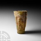 Roman Yellow-Green Glass Mythological Beaker
Late 1st -early 2nd century A.D. A mould-blown yellow-green glass beaker of tapering cylindrical form, d...