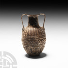 Roman Sidonian Glass Amphoriskos
1st century A.D. A mould-blown glass amphoriskos composed of an ovoid body, cylindrical neck, everted rim and twin a...