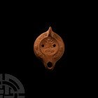 Roman Redware Lamp with Radiate Head of Serapis
3rd-4th century A.D. A squat terracotta oil lamp with thick nozzle and lug handle, band of leaves and...