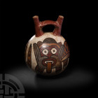 Pre-Columbian Nazca Feline Stirrup-Spout Vessel
3rd-6th century A.D. A roughly spherical polychrome ceramic stirrup bottle, featuring two tapering cy...